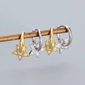 Detail of silver and gold star earrings with cubic zirconia charms hanging on a rod