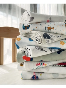 Detail of stacked bamboo cotton muslin swaddle blankets with colorful cartoon patterns
