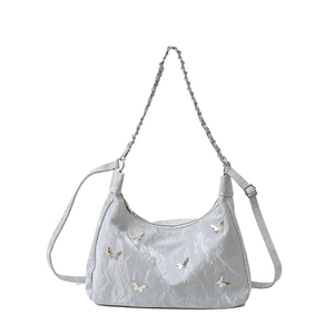 Elegant light blue wrinkled fabric shoulder bag with butterfly metal accents and chain strap