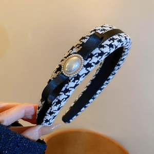 Detailed view of houndstooth headband with black bow and large pearl embellishment