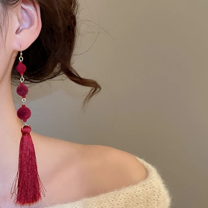 Detail view of burgundy flocked beads and long silky tassels on a vintage ear hook