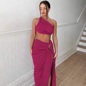 Detail of fuchsia two-piece set featuring one-shoulder crop top and high-slit maxi skirt