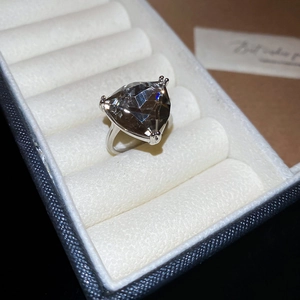 Macro shot of a silver ring featuring a large triangle-cut smoky grey gemstone in a jewelry box