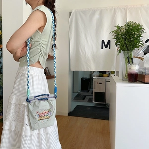 Detail of light green bag with carousel embroidery and blue-white braided rope strap