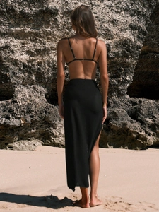 Back view of a black bikini top and matching knit maxi skirt with side slit on a beach
