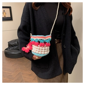 Detail of hand-knit cherry bucket bag with colorful crochet texture and pearl strap