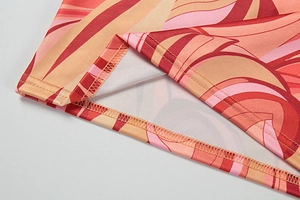 Detail of double-needle hem on dress featuring warm abstract wave print and fine stitching