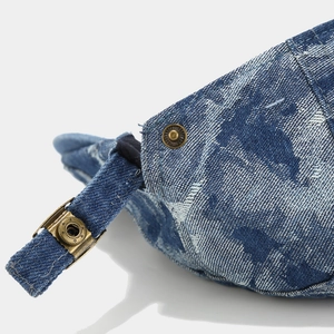 Detailansicht der gewaschenen Denim-Baskenmütze mit bronzener Metallschnalle und Ziernaht