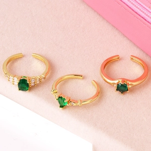 Detailed shot of three gold adjustable rings featuring emerald-cut zircon on pink velvet