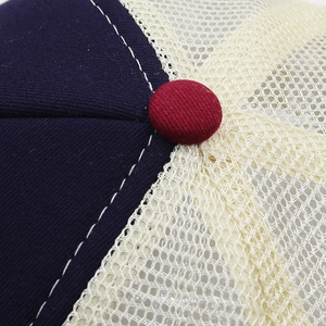 Detail of navy canvas and off-white mesh trucker hat with contrast stitching and top button