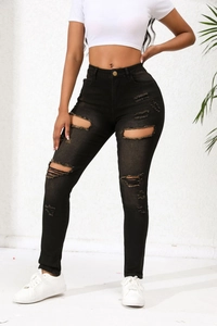Gros plan détaillé sur les déchirures d'un jean en denim noir à coupe ajustée