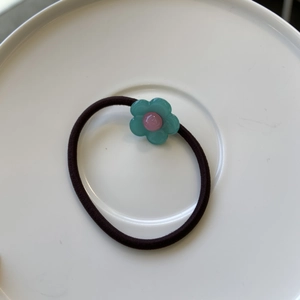 Gros plan d'un chouchou fleur sarcelle avec centre rose sur une assiette en céramique blanche