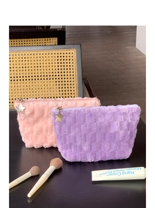 Detail of plush checkered makeup bags with star-shaped zipper pulls and soft texture