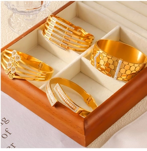 Detailed shot of four gold hollow titanium steel bracelets with rhinestones in a jewelry box