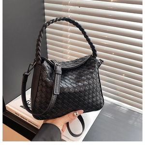 Detail of black leather woven handbag featuring checkered texture and adjustable strap