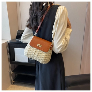 Detail of straw crossbody bag with brown leather flap and golden twist lock closure