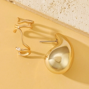 Detail of elegant gold-plated ear cuff and drop earring with cubic zirconia on stone base