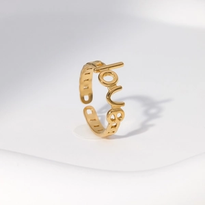 Macro detail of gold-plated stainless steel ring featuring the word 'love' engraving
