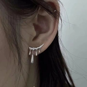 Close-up of liquid silver metallic earrings in a minimalist fluid streamlined shape