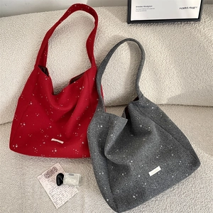 Dettaglio delle borse hobo in lana rossa e grigia con stelle bianche ed etichetta logo