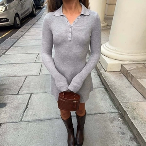 Close-up of a grey knitted long sleeve dress with a polo collar and button details