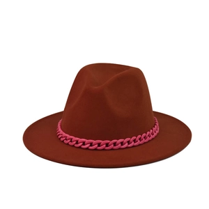 Close-up of rust red wool fedora with vibrant pink chunky chain link decoration