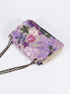 Close-up of purple floral embroidery and shiny sequins on the linen shoulder bag fabric