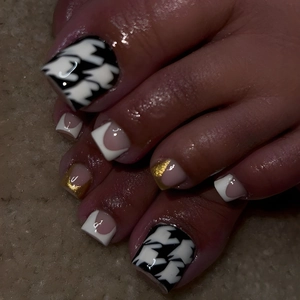 Detail shot of houndstooth and French tip press-on toenails in black, white, and gold