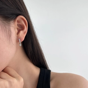Close-up of S925 sterling silver heart earrings with geometric zircons on model