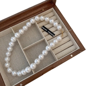 French vintage white pearl necklace with gold clasp in a wooden jewelry display case