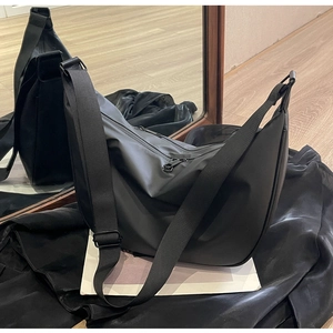 Close-up of black nylon dumpling bag with adjustable fabric shoulder strap and large capacity