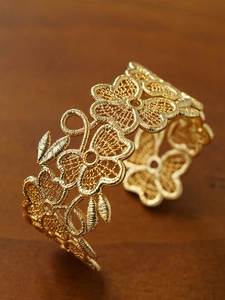 Detailed macro view of vintage 18k gold plated open cuff with intricate floral lace texture