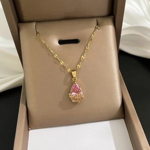 Vue détaillée du pendentif en cristal rose en forme de poire sur chaîne dorée