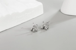 Detailed view of silver balloon dog stud earrings on minimalist stone background