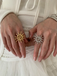 Detailed view of chunky gold and silver sunburst rings with spiral texture on hands