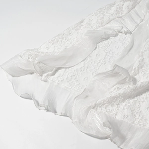 Gros plan détaillé du tissu en dentelle blanche avec bordure à volants et texture perlée