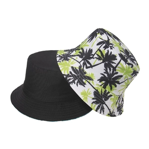 Detail of two-pack bucket hats featuring solid black and tropical green palm leaf prints