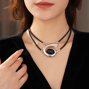 Detail of double-layer black leather necklace with silver swirl pendant and black gemstone