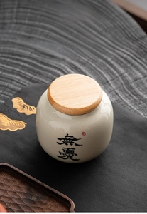 Detail of a mini ceramic tea jar with Chinese calligraphy and a natural bamboo lid