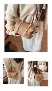 Detail view of khaki pleated Boston bag with twin handles and adjustable crossbody strap