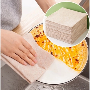 Absorbent beige dishcloth cleaning oily white plate with stacked towels in the corner