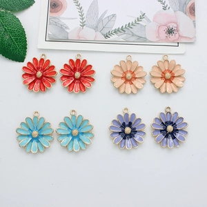 Flat lay of colorful daisy flower enamel alloy pendants in red, pink, blue, and purple tones