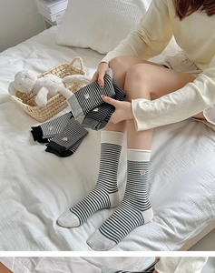 Detailaufnahme von gestreiften Baumwollsocken mit Bärenstickerei in gemütlichem Heim