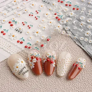 Macro shot of 5D embossed nail stickers with white daisies and red cherry patterns
