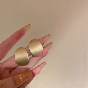 Minimalist matte gold irregular oval geometric stud earrings with a brushed metal finish