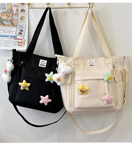 Detail view of nylon tote bags in black and cream featuring colorful star charms and logo