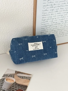 Detail shot of blue denim organizer bag with white bow pattern and cream zipper closure