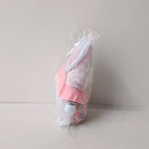 Side view of pink Easter rabbit gnome plush doll in transparent protective packaging