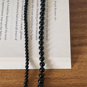 Black agate beaded necklace in 4mm and 6mm sizes on a minimalist background