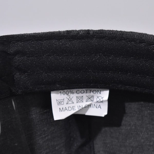 Detailed macro view of the 100% cotton inner label and wash care icons on baseball cap